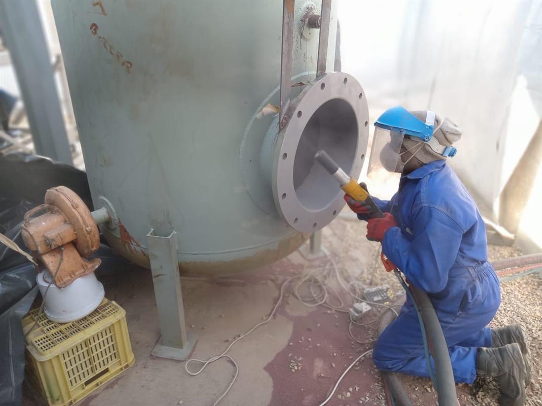 Technician abrasive blasting a pump casing before coating